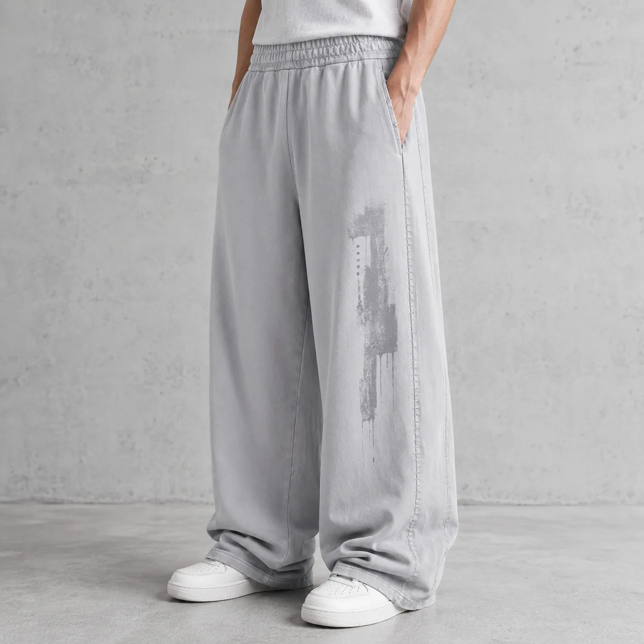 Model wearing light grey snow-washed panelled cotton joggers with representative embroidery